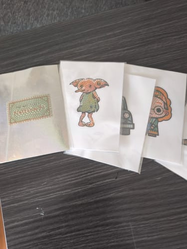 Customer's Harry Potter Crystal Art stickers, including Dobby, fanned out next to the shiny sticker album on a table.