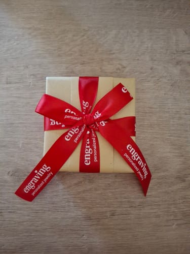 Customer's small gift box with premium gift wrapping, tied with a red ribbon in a bow.