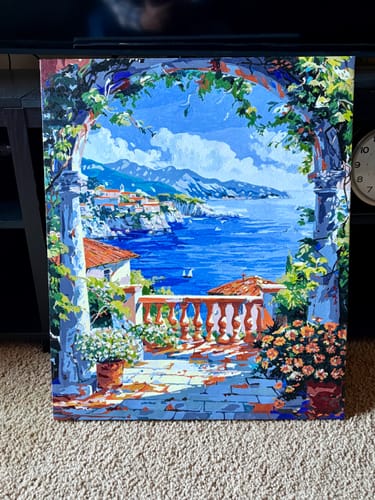 Customer's completed Amalfi Terrace paint-by-numbers kit, showing a colorful coastal view from a stone terrace.