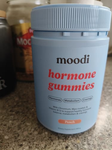 Customer's light blue container of Peach Hormone Gummies sitting on a kitchen counter.