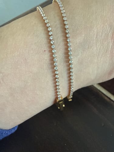 Customer showing two dainty Niyah White Crystal Gold Bracelets layered on their wrist.