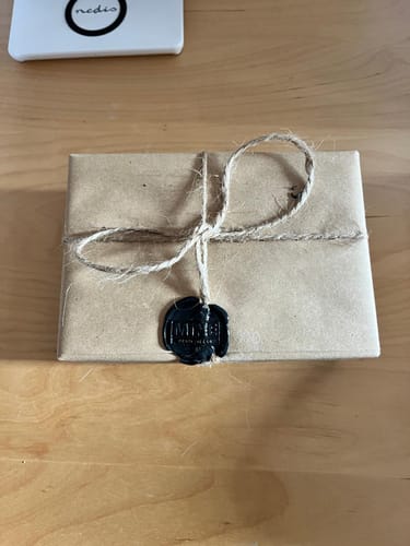 Il recensore mostra l'elegante confezione del suo profumo OUD, incartata con sigillo in ceralacca nera.