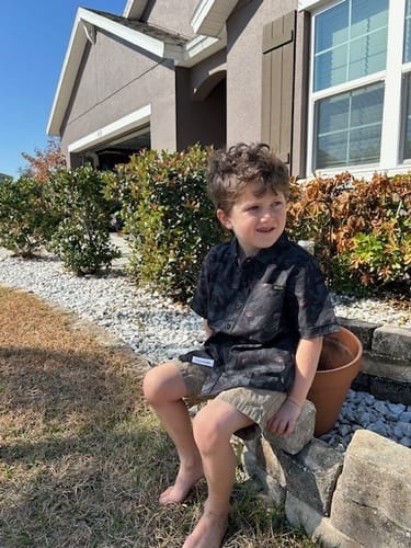 Reviewer's child sitting outside in the dark How to Train Your Dragon shirt, showing the visible white tag at the hem.