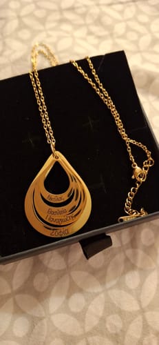 A customer's engraved gold Celestial Necklace with four names on the pendant, shown inside its box.