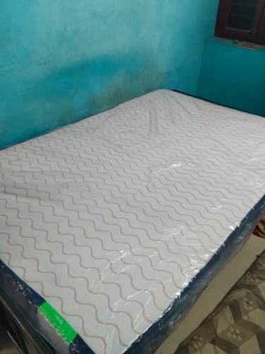 Customer's Flo waterproof mattress protector with a wavy pattern, shown on a bed in its packaging.