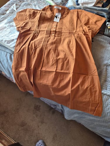 Customer's new Ivory Fields Smock Dress in camel brown, laid out flat on a bed.