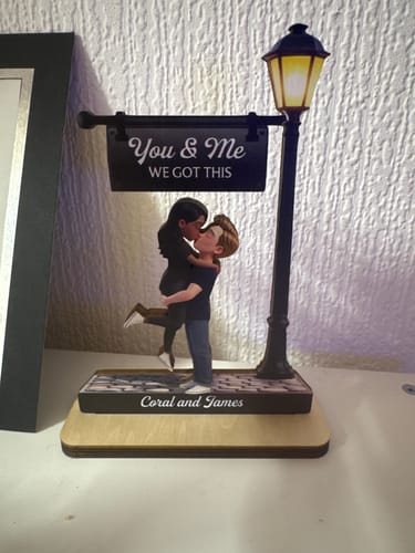 Customer's personalized wooden plaque of a couple kissing under a lit lamppost, customized with the names 'Coral and James'.