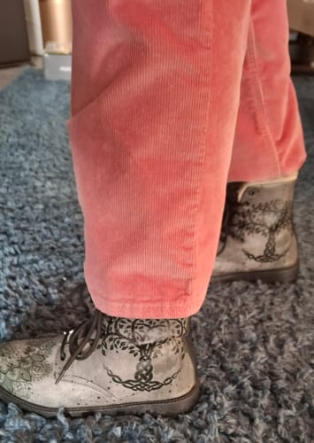 Un client porte les Boots Yumkaax grises avec un motif d'arbre et un pantalon rose en velours côtelé.