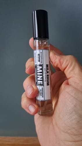 Recensore tiene in mano il piccolo flacone di profumo MILK RHUM.