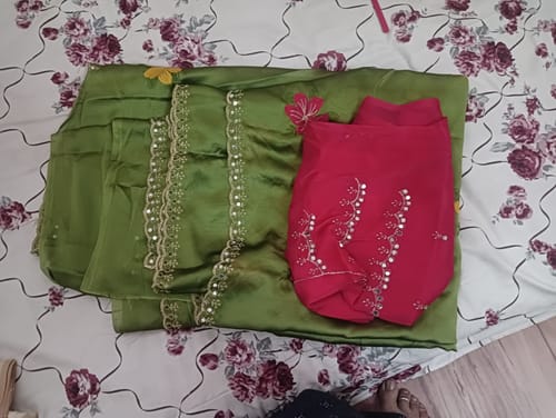 Reviewer's folded green saree and pink blouse piece showing the mirror work.