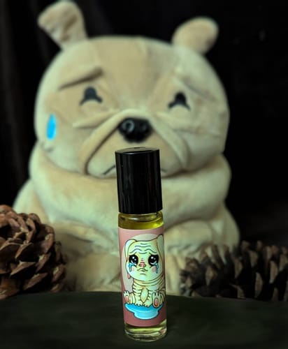 Customer's Squonk Nugget rollerball bottle with a cartoon label, displayed in front of a sad-looking plush toy and pinecones.