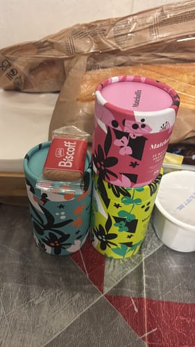 Cliente muestra dos botes de Té Matcha Premium, uno rosa y otro turquesa, con un diseño floral.