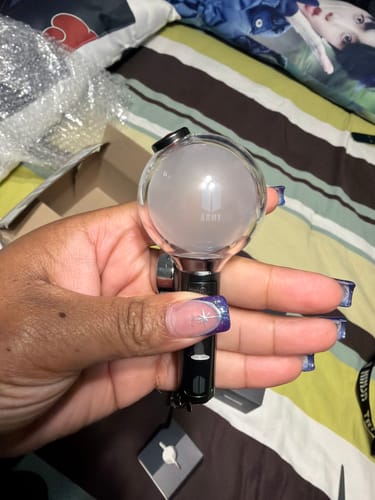 A reviewer's hand holding the BTS Official Light Stick Keyring SE, showing its size.