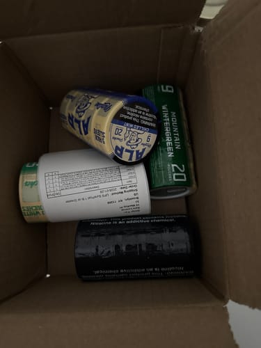 Customer's unboxing photo of a shipping box containing a green roll of Mountain Wintergreen Nicotine Pouches among other items.