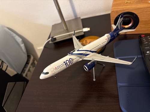 Customer's detailed GEMINI200 Delta A321neo model airplane with '100 Years' livery, shown on its stand on a desk.