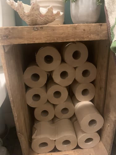 Customer's unbleached bamboo toilet paper rolls stacked neatly in a rustic wooden crate.