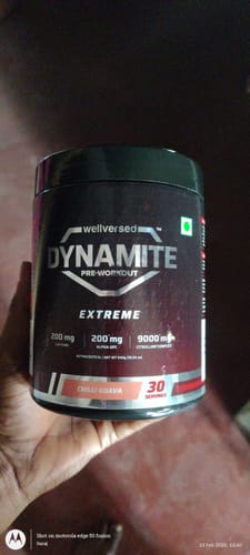 Customer's hand holding the black tub of Dynamite Pre-Workout EXTREME, showing the Chilli Guava flavor.