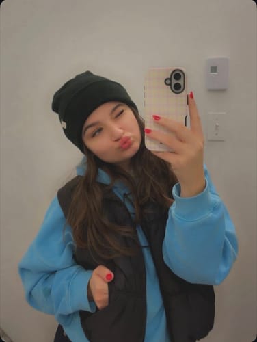 Reviewer holds up their phone in a mirror selfie, showing off the light-colored Divine phone case.