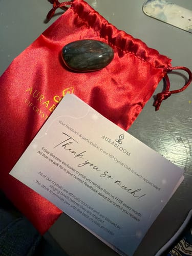Customer's polished Labradorite crystal from the monthly club with its red pouch and a thank you card.