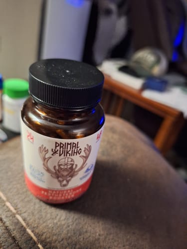 A customer's brown bottle of Primal Viking supplement with a black cap, shown sitting on a textured surface.