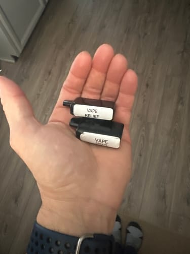 Customer's hand holding two small, black disposable vapes, including the Create Vape.