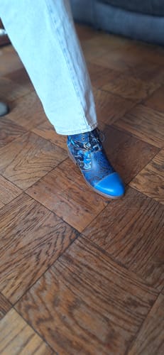 Customer's foot wearing the blue patterned Midnight Blossom Ankle Boot with light-wash jeans.