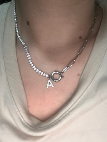 Eine Kundin trägt die silberne Tennis Letter Halskette mit einem 'A'-Anhänger und einem zweigeteilten Kettendesign.