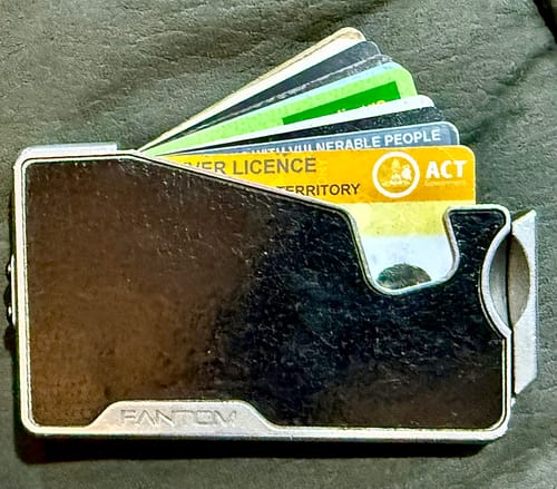 Customer's wallet fanned open with multiple cards, showing how the SPOTMINDERS Tracking Card PRO fits discreetly inside.