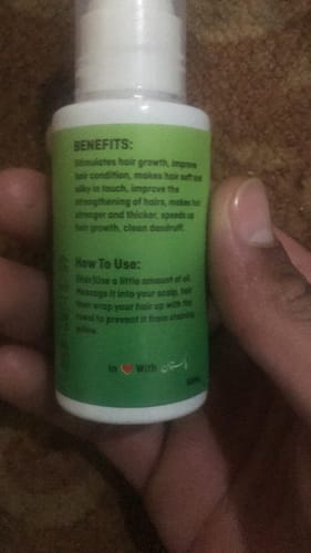 Reviewer's close-up of the Coriander Oil bottle, showing the green label with benefits and instructions.