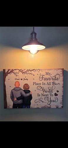 Customer's personalized 'Favorite Place' poster of a couple hugging, displayed on a wall under a warm overhead light.