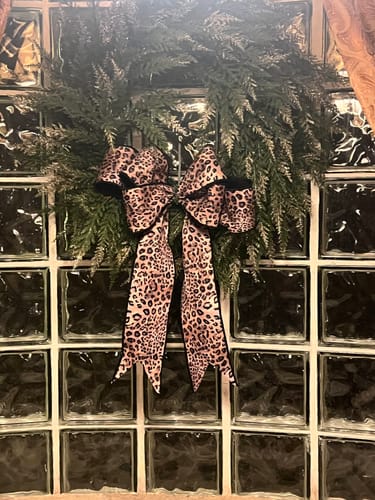Customer's leopard print ribbon used to make a large, beautiful bow on a green wreath hanging on a glass block wall.