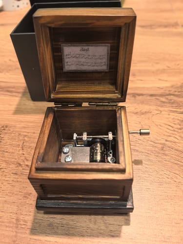 Reviewer's open Phasmophobia Music Box on a wooden table, showing the internal musical mechanism.