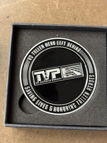 Customer's close-up of the black and silver Hard Days Challenge Coin in its box, reading "NO FALLEN HERO LEFT BEHIND".