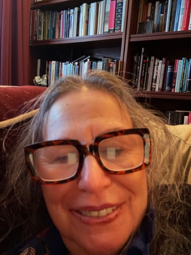 Close-up of a reviewer smiling while wearing the stylish tortoiseshell reading glasses.