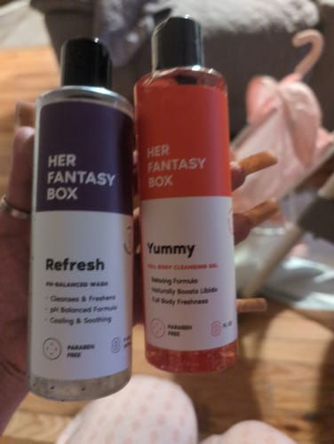 Customer holding up the Refresh and Yummy bottles from the Her Fantasy Two Pack Wash.