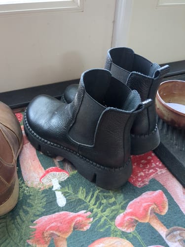 A reviewer's pair of black leather platform boots with thick soles, seen from a side angle.