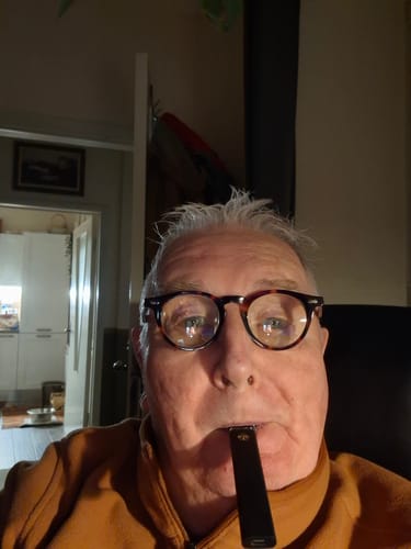 Customer holding the black ROLLZ THCA Vape in their mouth while wearing glasses.