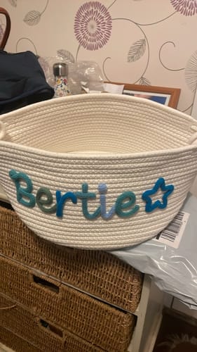 Customer's white knitted basket personalized with the name 'Bertie' and a star icon in blue yarn.