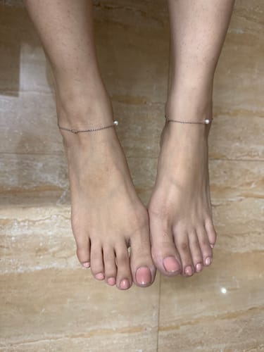 Customer wearing the Silver Pearls & Flower Anklet on both ankles, standing on a marble-style floor.