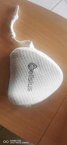 Vue par un client de la housse de coussin genoux Cellsius, avec le logo et la sangle, posée sur une table en bois.