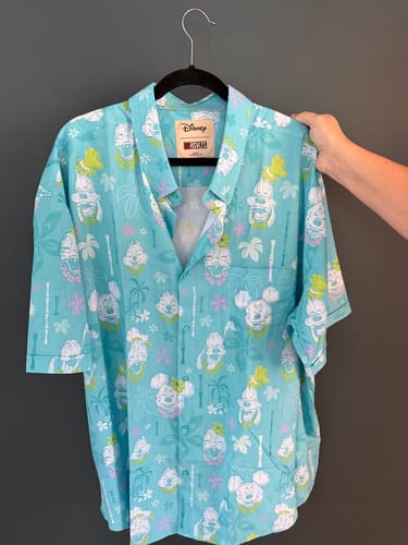 Customer's bright aqua Disney 'Island Smilin'' shirt on a hanger, showing the tropical character print.