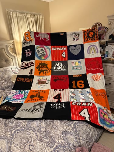 Customer's colorful Premium T Shirt Quilt, made from a daughter's elementary school shirts, spread across a bed.