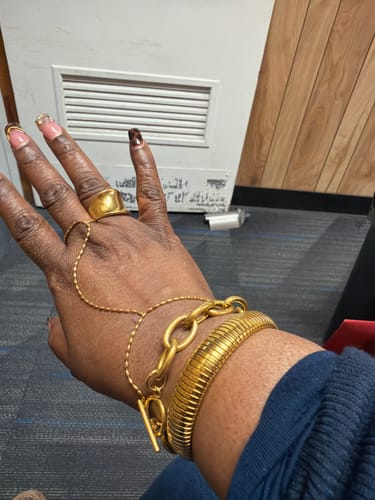 Customer's hand showing the stylish Zahara Handchain bundle, which includes a handchain and two thick gold bracelets.