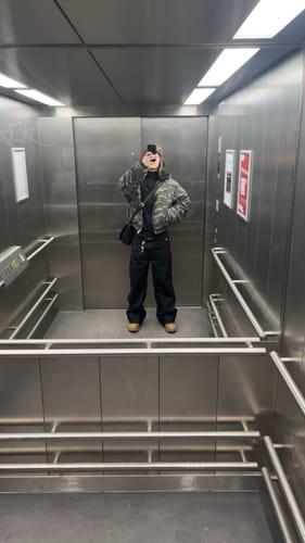 Reviewer in an elevator showing the fit of the black Raw Denim Jeans with a full outfit.