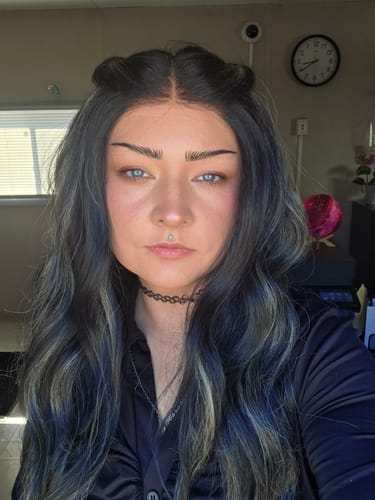 Close-up of a reviewer wearing the long, wavy Sensationnel Butta Lace wig, styled with a center part and two small buns.