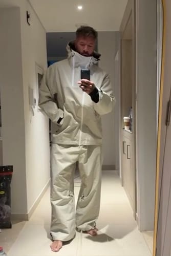 Reviewer in a hallway wearing the oversized off-white snow jacket with the face vent zipped up.