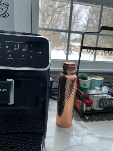 Customer's hand-hammered Pure Copper Water Bottle sitting on a kitchen counter.