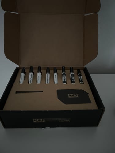 Un recensore mostra il 'Set campioni fresche e pungenti' aperto nella sua scatola, con le otto fiale di profumo allineate.