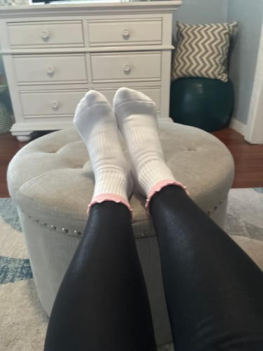Reviewer relaxing with their feet up, wearing white Pilates Princess socks with a pink frilly trim.
