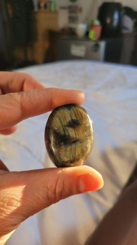 Close-up of a reviewer holding a dark, polished Monthly Crystal with a number '9' marking inside.